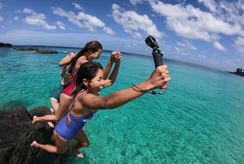 GoPro用ハンドグリップを持って海に飛び込む女性