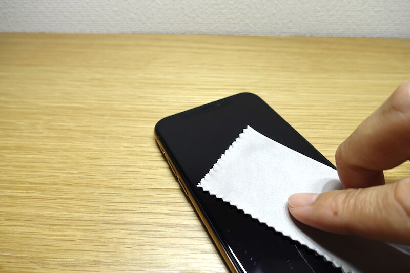 スマホをマイクロファイバーで拭いている
