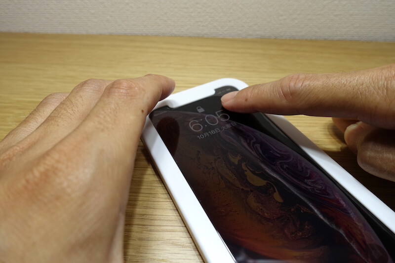 スマホを指で抑えてフィルムの空気を抜いている