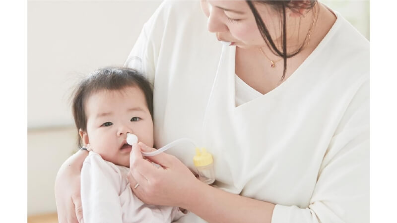 鼻水すい器で鼻水を取るママ