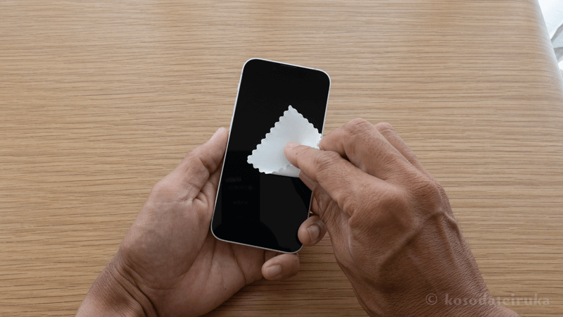 スマホをマイクロファイバーで拭いている
